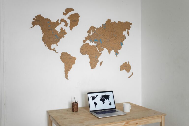A minimalist workspace with a laptop and cork world map wall art.